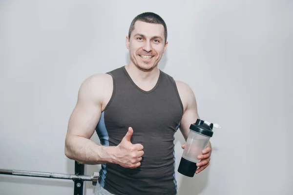 Ο αθλητής πίνει νερό από ένα σέικερ στο εκπαιδευτικό κέντρο. ανάπαυσης μεταξύ ασκήσεων στο γυμναστήριο — Φωτογραφία Αρχείου