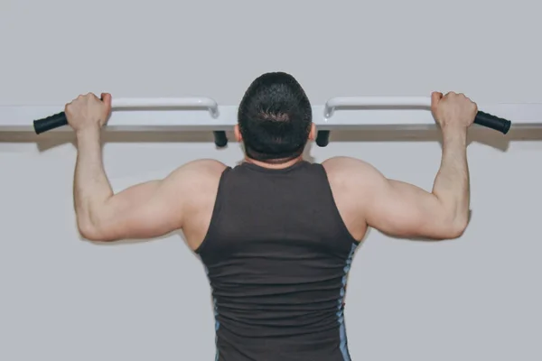 Atleta entrena los músculos de la espalda en el centro de entrenamiento. pull-ups en la barra horizontal en el gimnasio —  Fotos de Stock