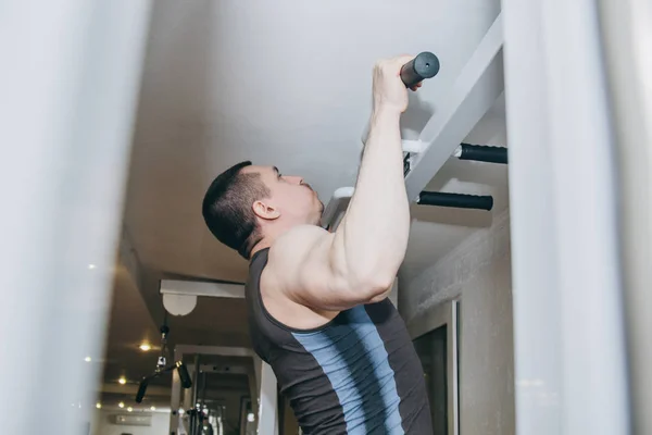 Atleet traint de rugspieren in het centrum van de opleiding. pull-ups op de horizontale balk in de sportschool — Stockfoto