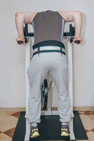 Athlète entraîne les muscles du dos dans le centre d'entraînement. pull-ups sur la barre horizontale dans la salle de gym — Photo