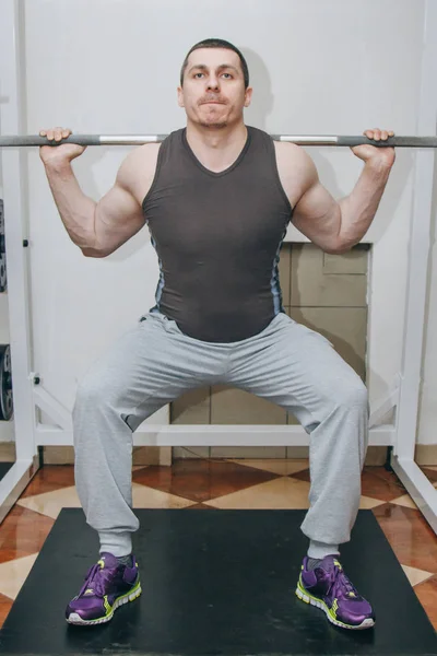 İyi eğitimli bir atlet bir eğitim merkezinde bacak kaslarını eğitir. spor salonunda barbell squats — Stok fotoğraf