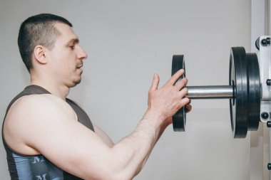 büyük elleri olan bir atlet eğitim merkezinde eğitim aparatları için metal diskler tarafından ağırlık ekler. spor salonunda eğitim ekipmanları yakın çekim