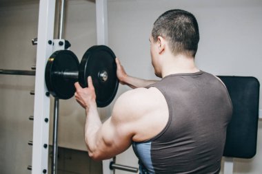 büyük elleri olan bir atlet eğitim merkezinde eğitim aparatları için metal diskler tarafından ağırlık ekler. spor salonunda eğitim ekipmanları yakın çekim