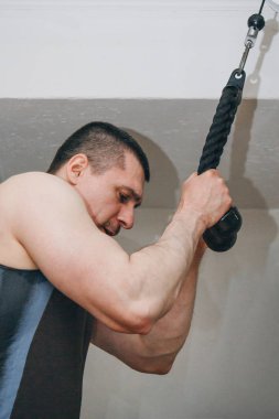 atlet siyah bir arka plan üzerinde eğitim merkezinde bir eğitim makinesi ile triceps eller trenler. spor salonunda yakın çekim eğitim araçları