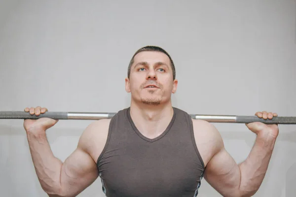 Um atleta bem treinado treina seus músculos das pernas em um centro de treinamento. agachamentos barbell no ginásio — Fotografia de Stock