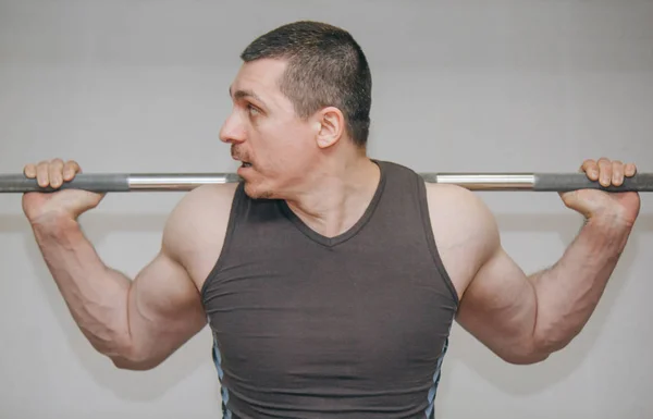 Un atleta bien entrenado entrena los músculos de sus piernas en un centro de entrenamiento. sentadillas de barra en el gimnasio —  Fotos de Stock