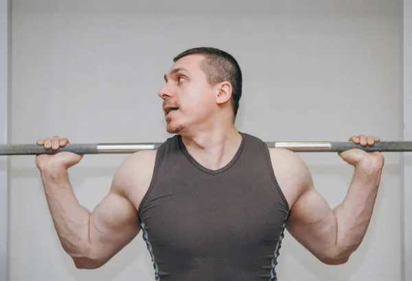 Um atleta bem treinado treina seus músculos das pernas em um centro de treinamento. agachamentos barbell no ginásio — Fotografia de Stock