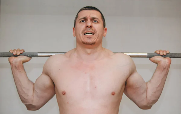 Un atleta bien entrenado entrena los músculos de sus piernas en un centro de entrenamiento. sentadillas de barra en el gimnasio —  Fotos de Stock