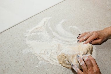 Kadın elleri beyaz bir mutfak masasında un ile hamur yoğurun. Üst te. pişirme hazırlık aşaması, pişirme