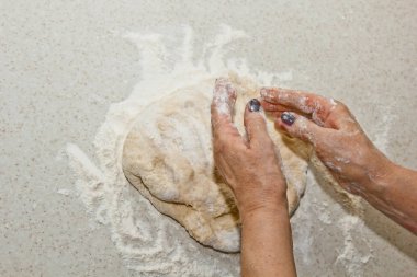 Kadın elleri beyaz bir mutfak masasında un ile hamur yoğurun. Üst te. pişirme hazırlık aşaması, pişirme