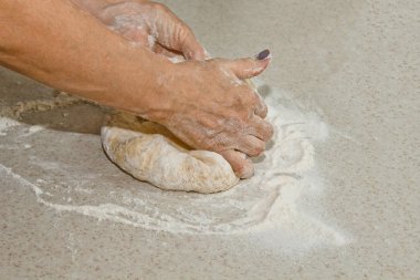 Kadın elleri beyaz bir mutfak masasında un ile hamur yoğurun. Üst te. pişirme hazırlık aşaması, pişirme