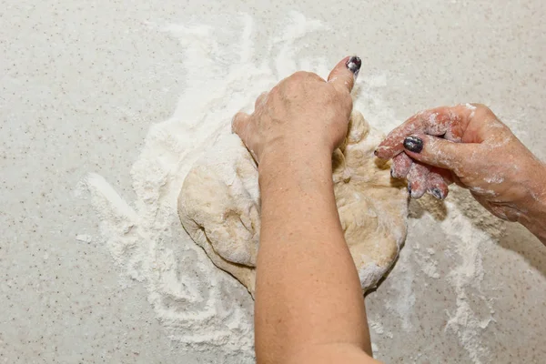 Женские руки месят тесто с мукой на белом кухонном столе. Вид сверху. стадии подготовки выпечки, приготовления пищи — стоковое фото