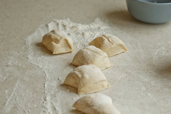 chopped raw kneaded dough into pieces on the table against the background of the kitchen interior. cooking baking dish
