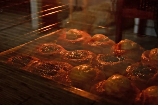 Een bakje vol Cheesecakes met kwark ligt in de oven achter het glas. koken bakken. bakvoorbereidings fase. Close-up met reflectie — Stockfoto