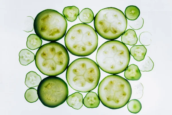 Grüne durchscheinende Gurkenscheiben auf dem Hintergrund hellweißen Lichts in Großaufnahme. transparente Scheiben mit Gemüse. Textur von Kaleidoskopmustern im Makro — Stockfoto