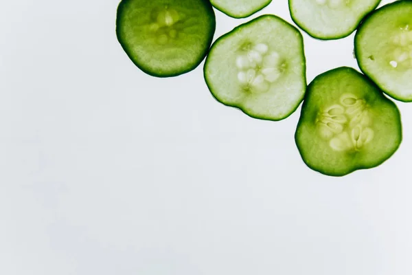 Зеленый полупрозрачный ломтик огурца на фоне яркого белого света крупным планом. прозрачные диски с овощами. текстура калейдоскопов в макросах — стоковое фото