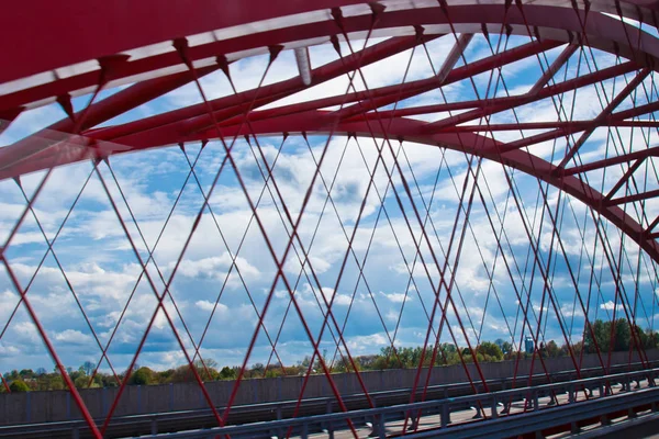 Raios de uma ponte arqueada vermelha close-up contra um céu azul. textura da treliça das partes da ponte de aço. transição cortada para o outro lado — Fotografia de Stock