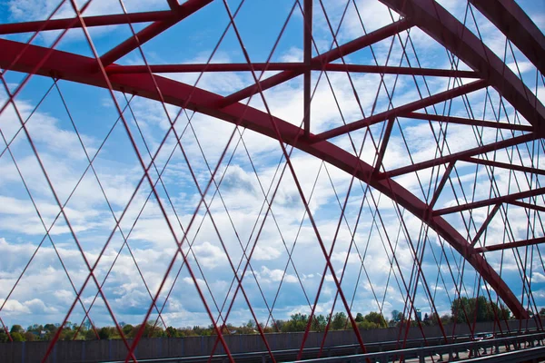 Strahlen einer roten Bogenbrücke in Nahaufnahme vor blauem Himmel. Textur des Gitters der Stahlbrücke. abgeschnittener Übergang auf die andere Seite — Stockfoto