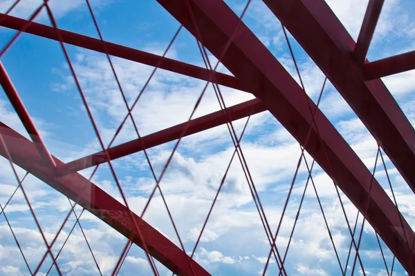 Strahlen einer roten Bogenbrücke in Nahaufnahme vor blauem Himmel. Textur des Gitters der Stahlbrücke. abgeschnittener Übergang auf die andere Seite — Stockfoto