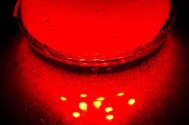 köpüren su ve duman la dolu bir cam nargile şişesi kırmızı karanlıkta parlıyor. karanlıkta ışıltı