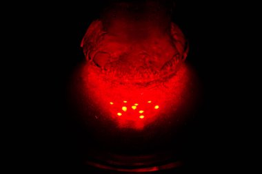 köpüren su ve duman la dolu bir cam nargile şişesi kırmızı karanlıkta parlıyor. karanlıkta ışıltı