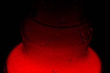 köpüren su ve duman la dolu bir cam nargile şişesi kırmızı karanlıkta parlıyor. karanlıkta ışıltı