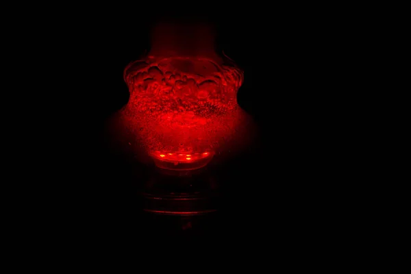 거품이 나는 물로 가득 찬 유리 후카 플라스크와 연기가 붉은 색으로 어둠 속에서 빛납니다. 어둠 속에서 발광 — 스톡 사진