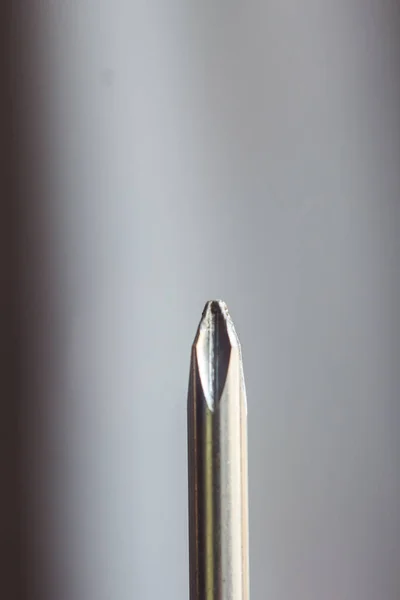Cabeça de metal cruzes chave de fenda close-up em um fundo borrado. ferramenta de mão de perto. espaço de cópia. vertical — Fotografia de Stock