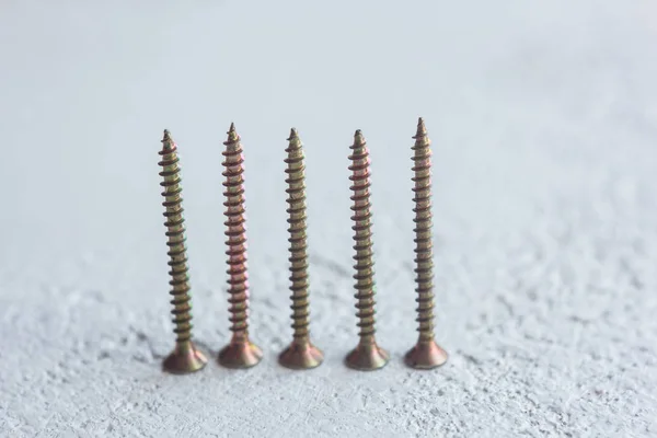 Tornillos de metal en el primer plano del árbol sobre un fondo borroso. pernos de primer plano sobre la mesa. espacio de copia — Foto de Stock