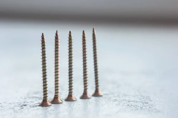 Tornillos de metal en el primer plano del árbol sobre un fondo borroso. pernos de primer plano sobre la mesa. espacio de copia — Foto de Stock