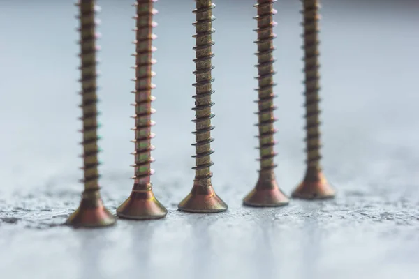 Tornillos de metal en el primer plano del árbol sobre un fondo borroso. pernos de primer plano sobre la mesa. espacio de copia — Foto de Stock