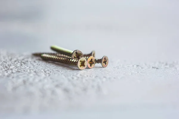 Tornillos de metal en el primer plano del árbol sobre un fondo borroso. pernos de primer plano sobre la mesa. espacio de copia — Foto de Stock