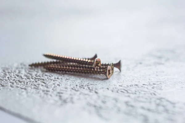 Tornillos de metal en el primer plano del árbol sobre un fondo borroso. pernos de primer plano sobre la mesa. espacio de copia — Foto de Stock