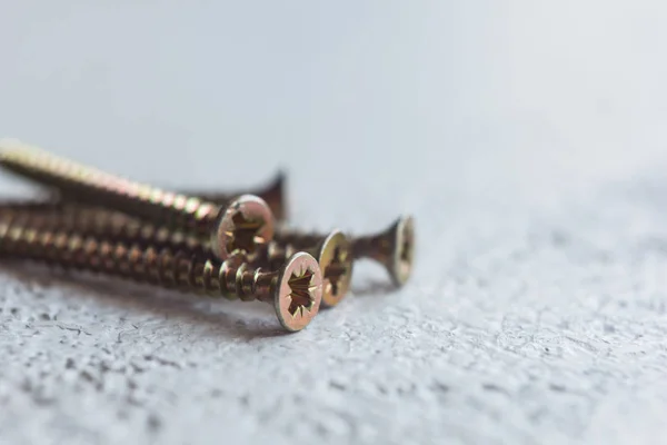 Tornillos de metal en el primer plano del árbol sobre un fondo borroso. pernos de primer plano sobre la mesa. espacio de copia — Foto de Stock