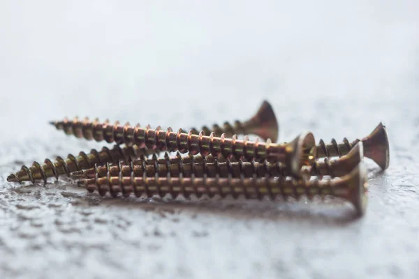 Tornillos de metal en el primer plano del árbol sobre un fondo borroso. pernos de primer plano sobre la mesa. espacio de copia — Foto de Stock