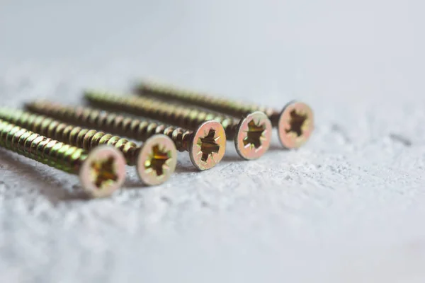 Tornillos de metal en el primer plano del árbol sobre un fondo borroso. pernos de primer plano sobre la mesa. espacio de copia — Foto de Stock