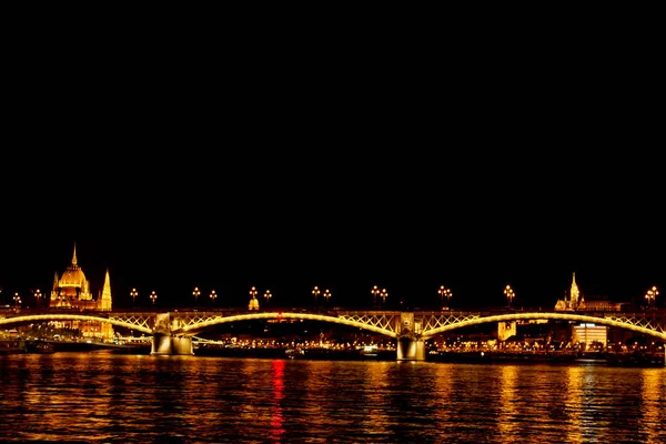 Nachtschwärmer, golden leuchtend. Die Brücke über die Donau wird von Glühbirnen beleuchtet. Foto aus dem Fluss — Stockfoto