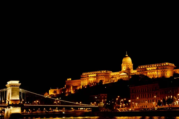 Night Budapest, glowing in gold. The chain bridge over the Danube is illuminated by light bulbs. photo from the river — Stock Photo, Image