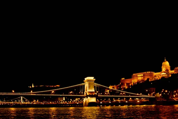 Nuit Budapest, rougeoyante d'or. Le pont de chaîne sur le Danube est éclairé par des ampoules. photo de la rivière — Photo