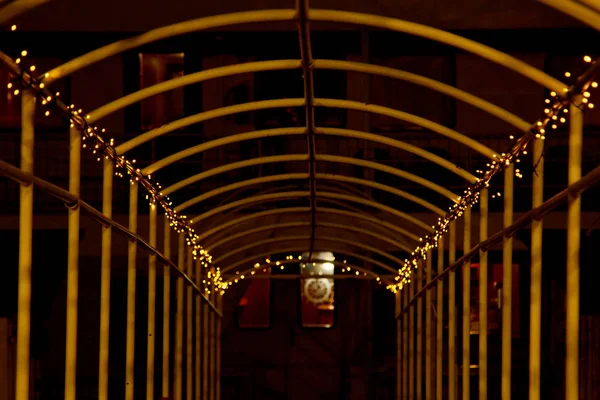 Arche métallique entrelacée d'une guirlande avec des lumières LED la nuit. manière dans la perspective — Photo