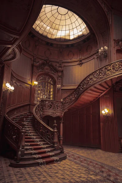 Old spiral wooden staircase with vintage railing indoors. luxury carved wood interior in the hall of an aristocratic palace. rare architecture with a glass dome ceiling. copy space — Stock Photo, Image