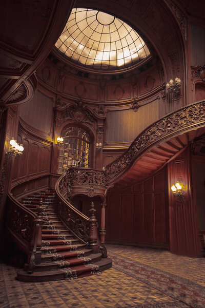 old spiral wooden staircase with vintage railing indoors. luxury carved wood interior in the hall of an aristocratic palace. rare architecture with a glass dome ceiling. copy space