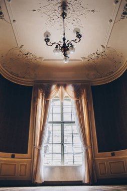 Güneşli bir günde eski perdeleri ve kare perdeleri olan ahşap pencereler. bej saten perdeler. Pahalı dekorasyonu olan boş bir odanın içinde. kolaj için arkaplan