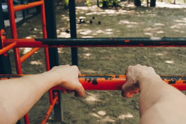 bir spor atletin elleri, eğitim katında Çekiciler için metal bir çapraz çubukta tutun. spor eğitimi açık havada. egzersiz birinci şahıs görünümü