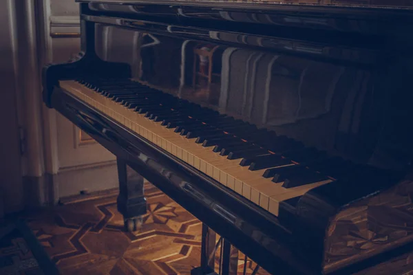 Egy fekete klasszikus zongora áll egy luxusszobában. klasszikus zeneeszköz közelről, barokk belső — Stock Fotó
