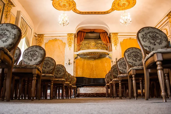 Μια ομάδα από vintage ξύλινες καρέκλες στέκεται σε διάφορες σειρές σε ένα μεγάλο παλιό δωμάτιο με πολυτελές εσωτερικό. κενό αμφιθέατρο στην αίθουσα συναρμολόγησης. αίθουσα για παραστάσεις χωρίς θεατές — Φωτογραφία Αρχείου