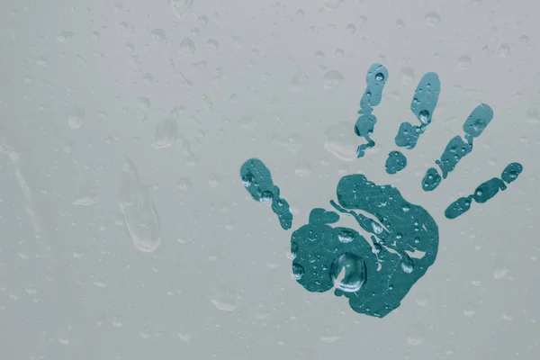 L'empreinte d'une paume humaine sur un verre translucide et brumeux. Des gouttes de pluie printanières sur une fenêtre brumeuse se referment. espace de copie arrière-plan flou — Photo