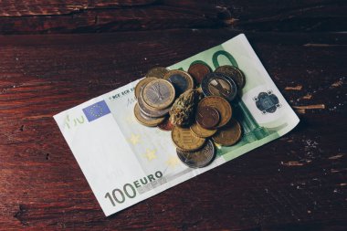 Bir kenevir tomurcuk yüz euro fatura ve sikke yakın çekim yatıyor. yasal laştırılmış yumuşak ilaçların satın alınması ve satılması. tıbbi esrar iş kavramı