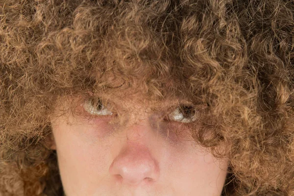 Retrato de um jovem europeu encaracolado com um olhar sério olhando para o seu cabelo longo com os olhos para cima. cabelo masculino muito exuberante cara. cabelo ondulação para homens — Fotografia de Stock