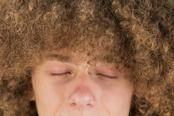 Retrato recortado de un joven europeo rizado con el pelo largo rizado y los ojos cerrados de cerca. pelo masculino muy exuberante de un chico. pelo rizado para los hombres. un candado de pasión. sueños de belleza — Foto de Stock